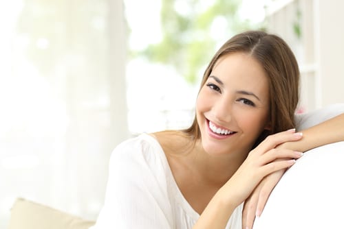 Pretty young woman leaning against the back of a chair smiling