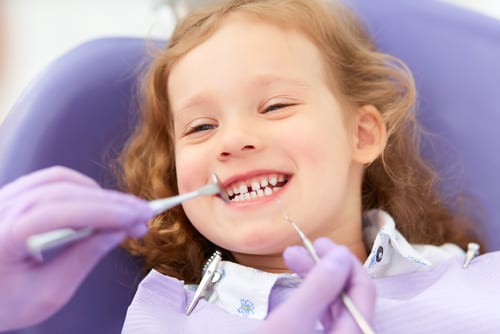 Young girl smiling while undergoing a dental examination