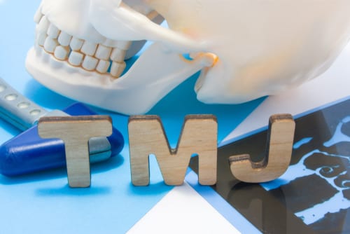 Scull and jawbone sitting on the initials TMJ