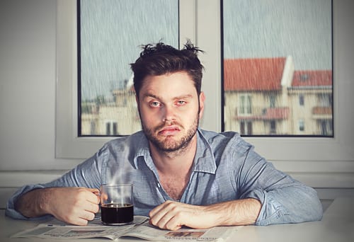 Tired man in pajamas drinking coffee