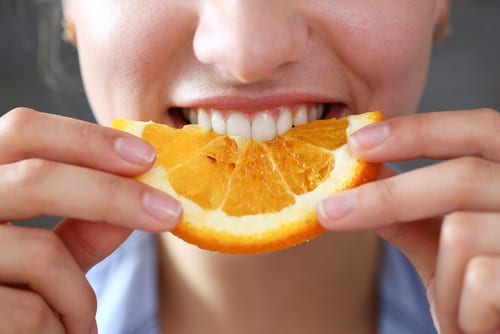 Woman biting into an orange slice