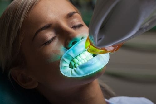 A patient undergoes teeth whitening with ultraviolet light.