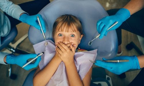 A child with a cavity is afraid of the dentist because of what her parents have said.