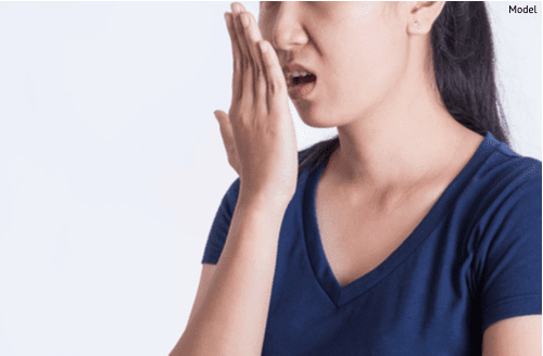 Asian woman checking her breath with her hand