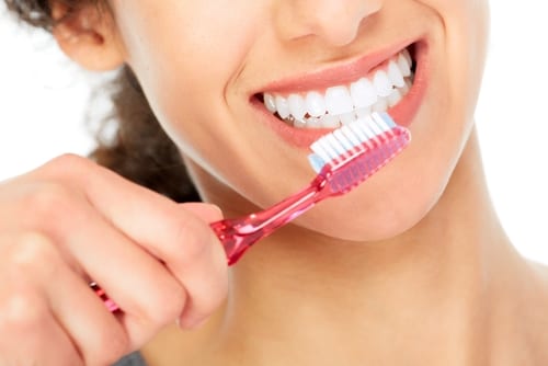 A woman maintaining a 45-degree toothbrush angle as she brushes her teeth for a minimum of two minutes