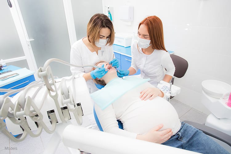 A pregnant woman receiving a routine check up to maintain a healthy oral hygiene.