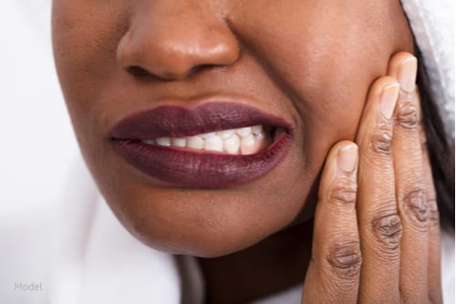 Woman wincing from a toothache.