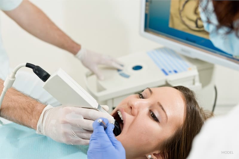 Woman at the dentist getting a treatment with dental tool in mouth.