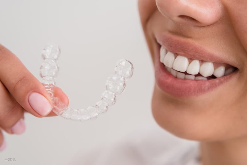 woman beautiful smile holding a transparent brace mold