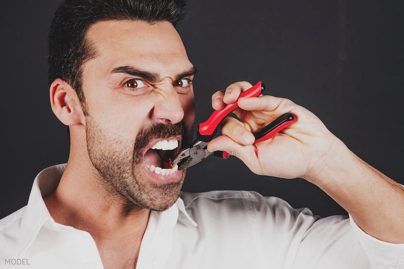 Man pulling out his tooth with pliers