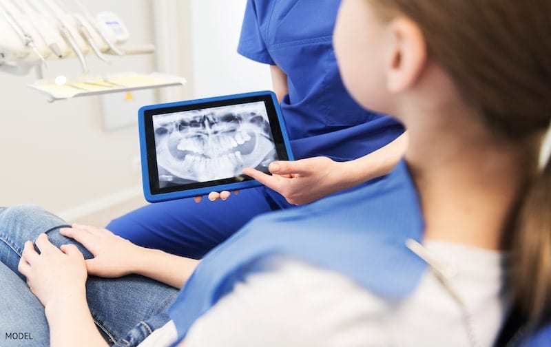 dentist showing teeth x-ray on tablet pc computer screen to patient