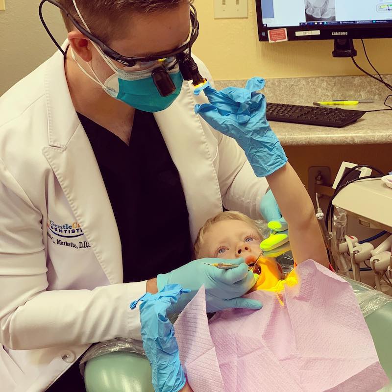 Dentist looking into the mouth of a young boy.