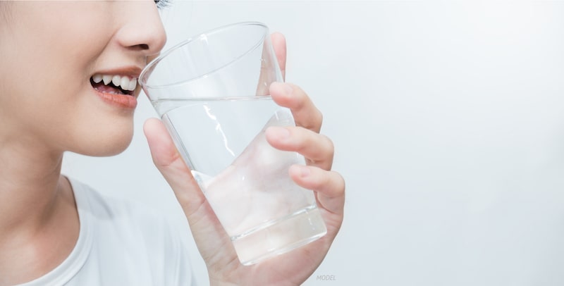 Close-up of young woman drinking a glass of water.