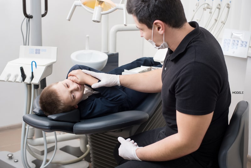 Little boy laying in a dentist chair with a dentist.