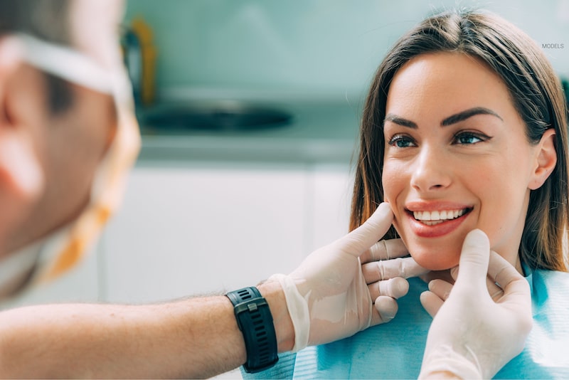 A dentist looks at a pretty woman's nice, white teeth.