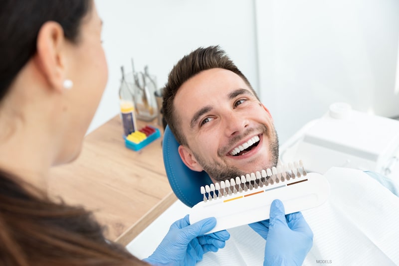 A man's teeth are color-matched before receiving a dental restoration.