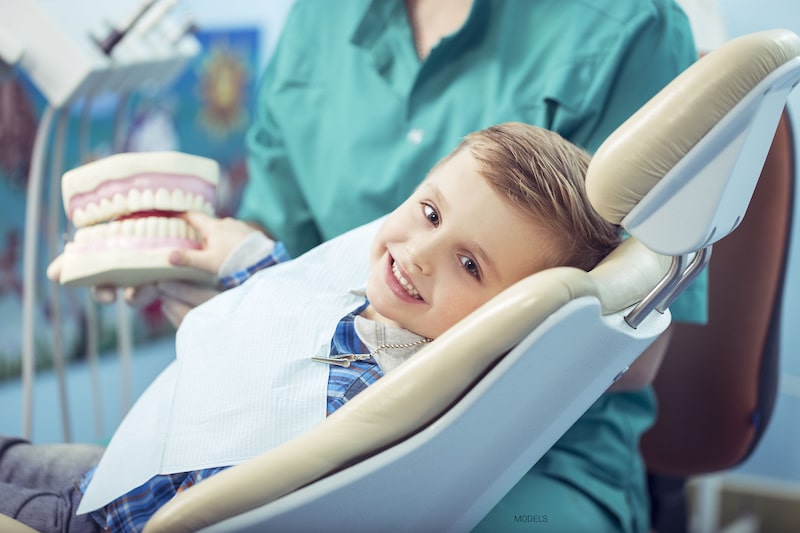 A little boy is happy and content while sitting in the dentist's chair.
