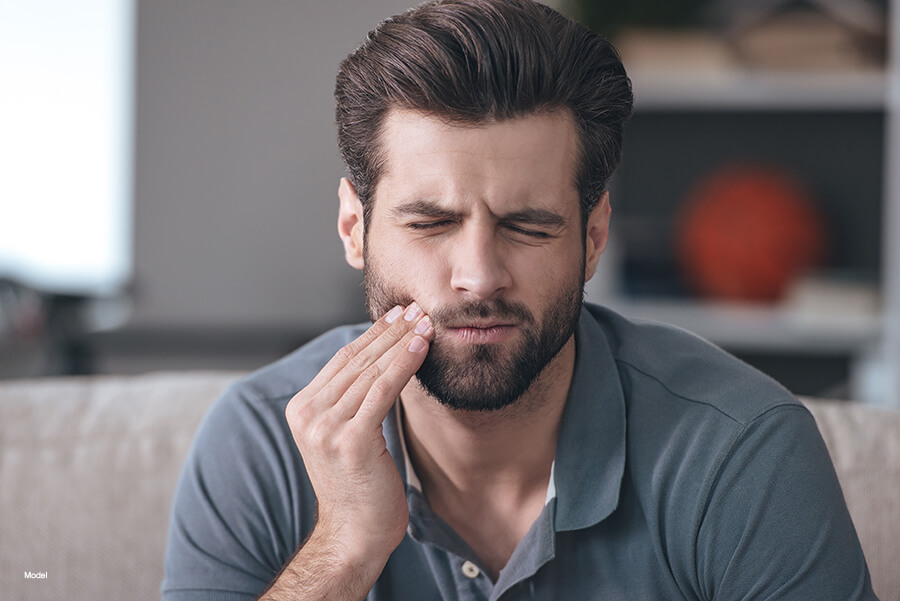 Man touching face and wincing due to toothache