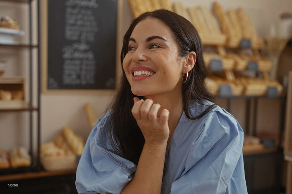 Woman at a cafe smiling in a blue shirt